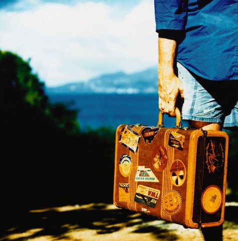 Hand Holding Suitcase Covered with Labels